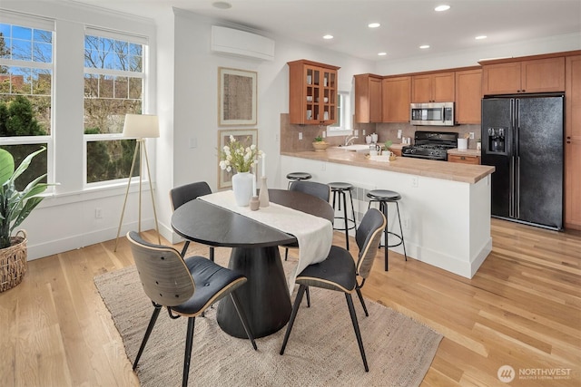 kitchen featuring a peninsula, black appliances, light countertops, glass insert cabinets, and tasteful backsplash