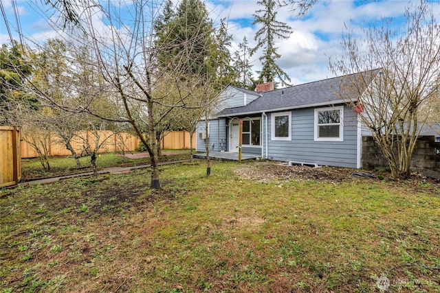 exterior space with a chimney, a shingled roof, a front yard, and fence