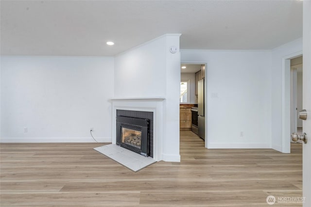 unfurnished living room featuring baseboards, light wood-style flooring, a fireplace with flush hearth, recessed lighting, and ornamental molding