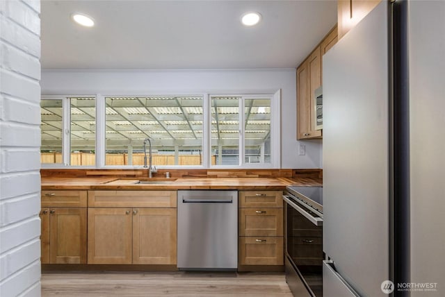 kitchen with wooden counters, recessed lighting, appliances with stainless steel finishes, and a sink