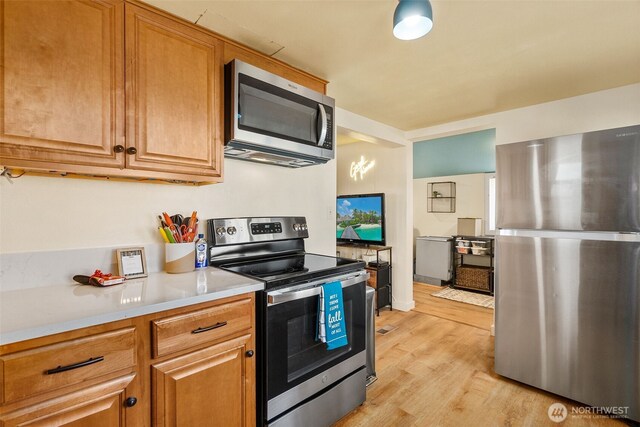 kitchen featuring brown cabinetry, stainless steel appliances, light countertops, and light wood finished floors