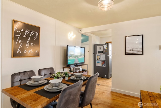 dining space with baseboards and light wood finished floors