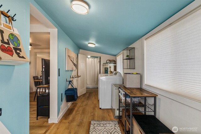 laundry room featuring laundry area, washer / clothes dryer, light wood-style floors, and water heater