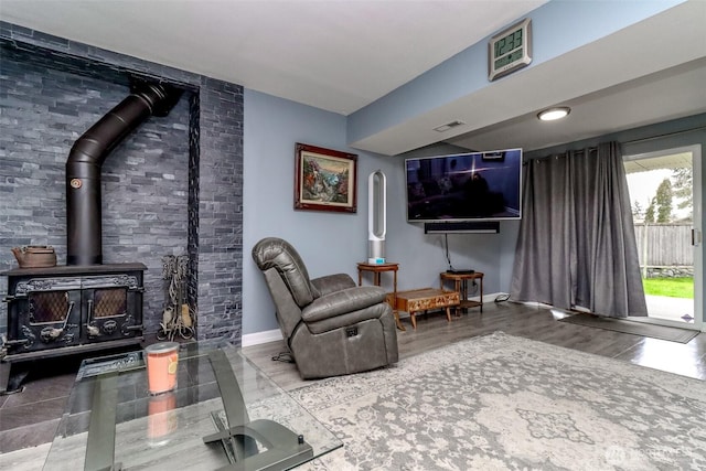 living area featuring visible vents, baseboards, and a wood stove