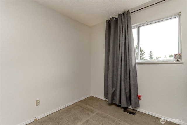 unfurnished room with visible vents, baseboards, carpet, and a textured ceiling