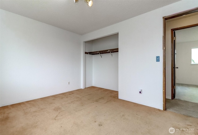 unfurnished bedroom with carpet, a closet, and a textured ceiling