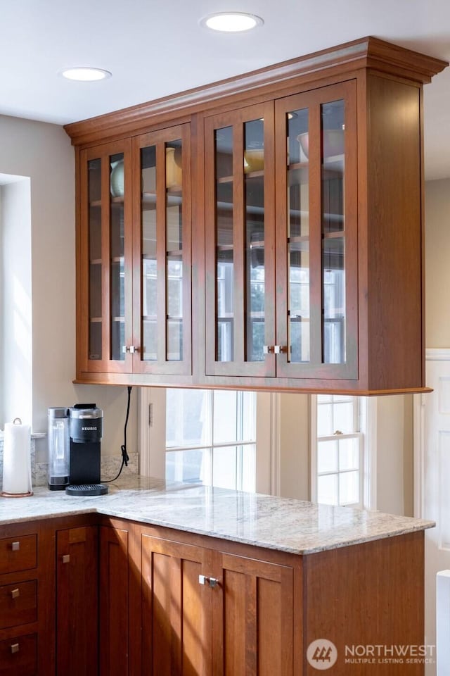 1120 Home Ave, Walla Walla, WA 99362 - kitchen with brown cabinetry, light stone countertops, glass insert cabinets, and a peninsula