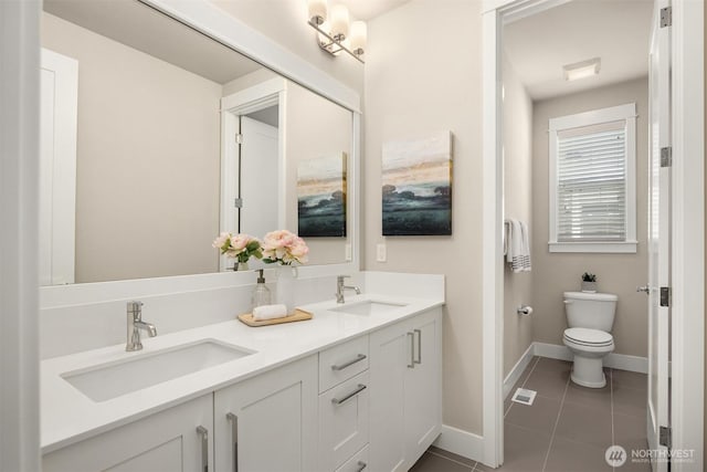 bathroom with a sink, toilet, double vanity, and tile patterned flooring