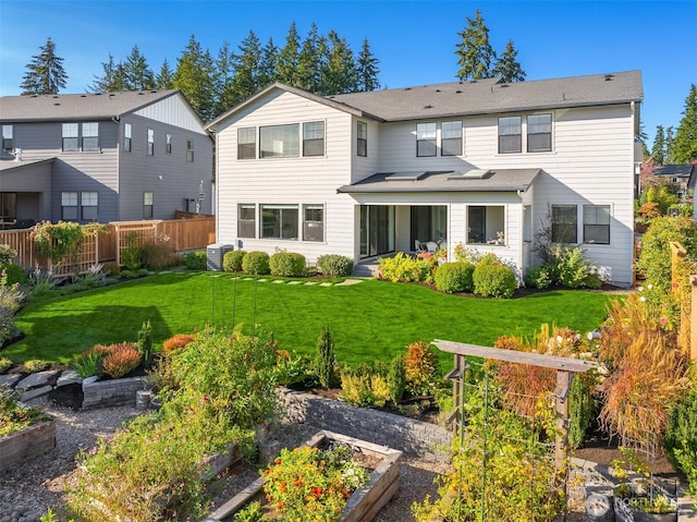 back of house with a lawn, a vegetable garden, and fence