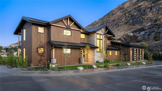 view of front of home featuring metal roof, stone siding, a garage, and a standing seam roof