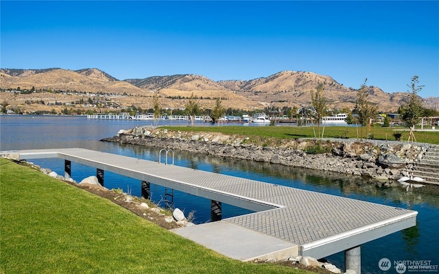 view of dock featuring a water and mountain view and a lawn