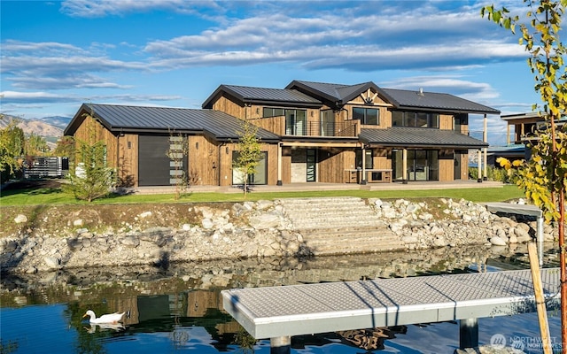 back of house featuring a balcony, metal roof, and a standing seam roof