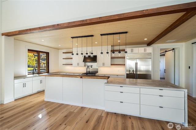 kitchen featuring open shelves, stainless steel built in fridge, light wood-style flooring, and a center island