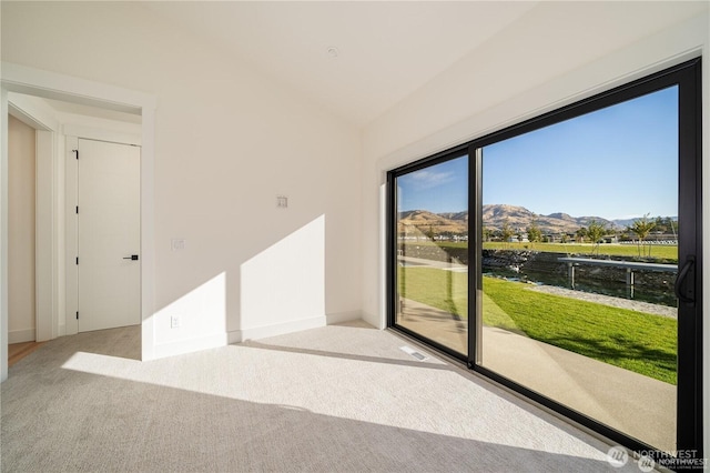 carpeted empty room featuring a mountain view, baseboards, and vaulted ceiling