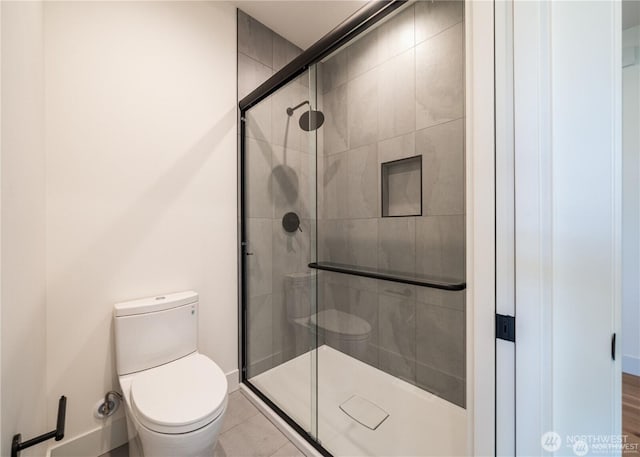 full bathroom featuring a stall shower, toilet, and baseboards