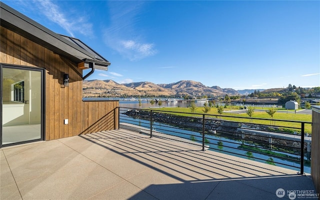 view of patio / terrace with a balcony and a water and mountain view