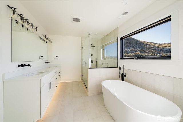 bathroom featuring double vanity, visible vents, a freestanding bath, and a shower stall