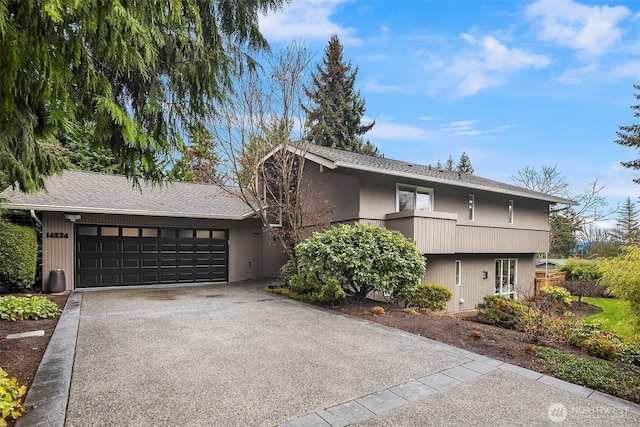 view of front of property featuring concrete driveway, an attached garage, and a shingled roof