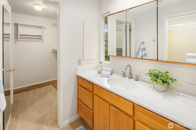 bathroom featuring vanity, a walk in closet, and baseboards