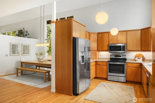 kitchen featuring brown cabinets, stainless steel appliances, light wood-type flooring, and light countertops