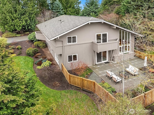 rear view of house featuring a patio area, a shingled roof, and fence