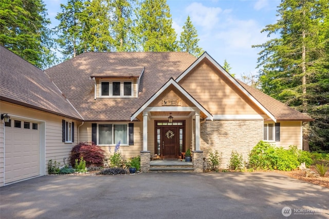 view of front of property with a garage, stone siding, roof with shingles, and aphalt driveway