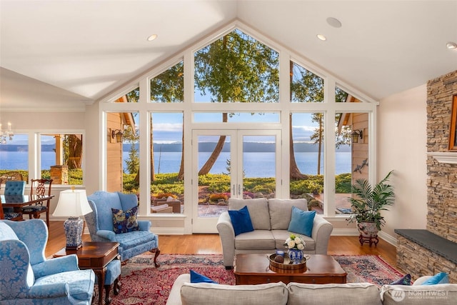 sunroom / solarium with a water view, an inviting chandelier, a healthy amount of sunlight, and vaulted ceiling