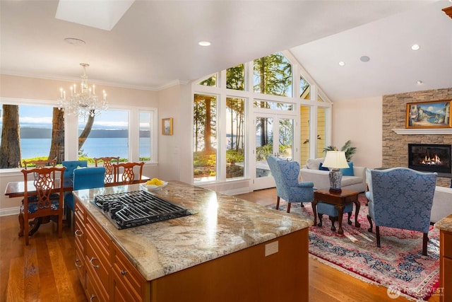 kitchen with brown cabinetry, a notable chandelier, a fireplace, and wood finished floors