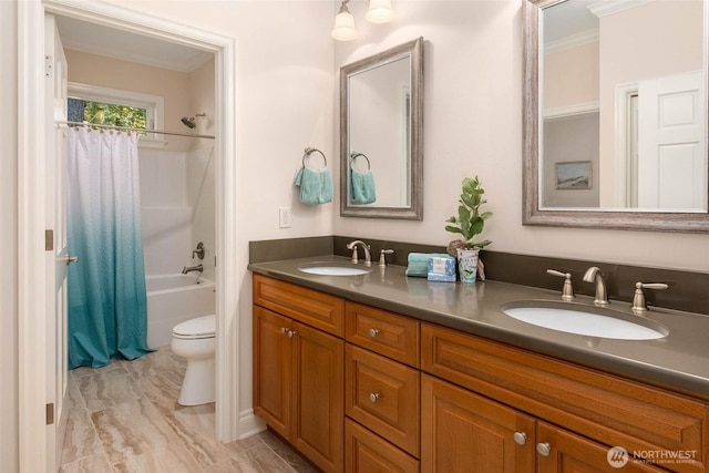 full bathroom with toilet, double vanity, ornamental molding, and a sink