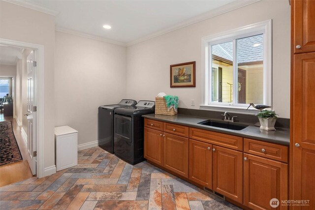 laundry room with crown molding, baseboards, washing machine and dryer, cabinet space, and a sink