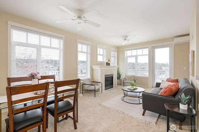 living room featuring a glass covered fireplace, plenty of natural light, a wall mounted air conditioner, and ceiling fan