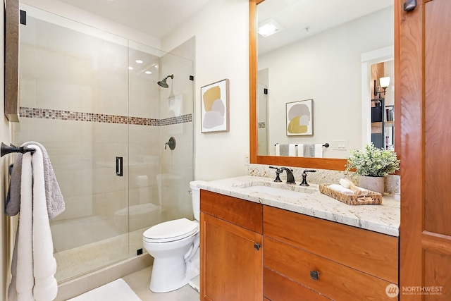 bathroom featuring vanity, a shower stall, and toilet