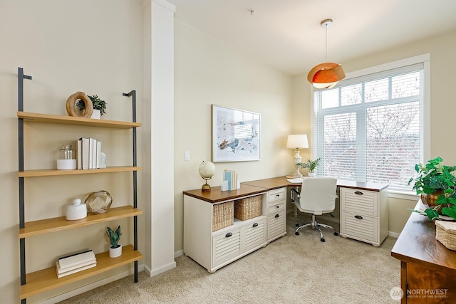 office area featuring baseboards and light carpet