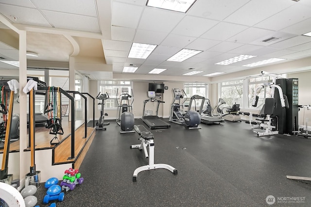 gym with a paneled ceiling and visible vents