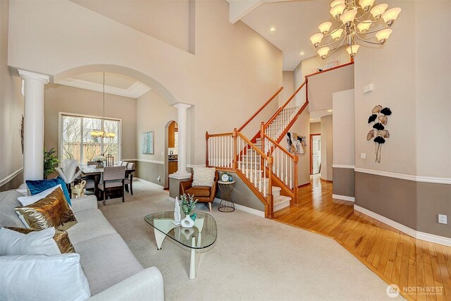 living room with a chandelier, stairway, ornate columns, and wood finished floors