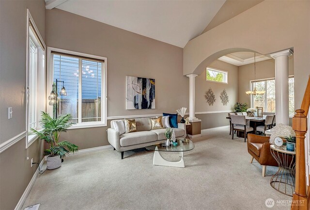 living room with ornate columns, arched walkways, carpet flooring, baseboards, and vaulted ceiling