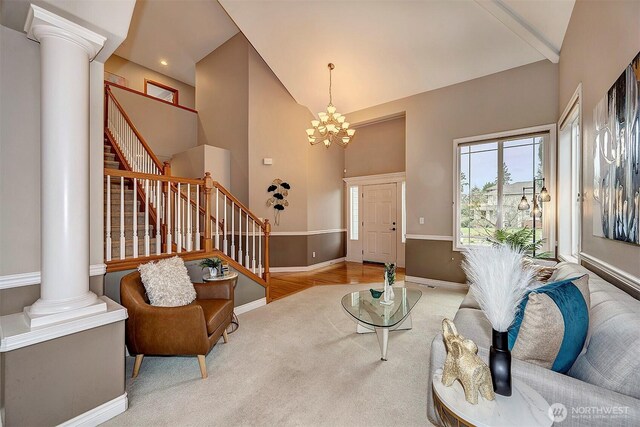 living room featuring stairway, baseboards, ornate columns, high vaulted ceiling, and a chandelier