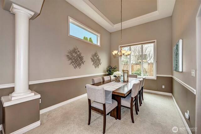 dining room with a healthy amount of sunlight, baseboards, carpet floors, a tray ceiling, and decorative columns