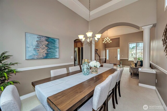 dining space featuring light colored carpet, a towering ceiling, and ornate columns