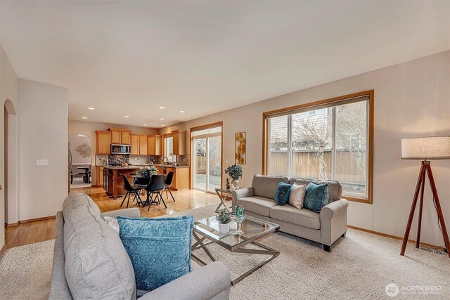 living room with recessed lighting, baseboards, arched walkways, and light wood finished floors