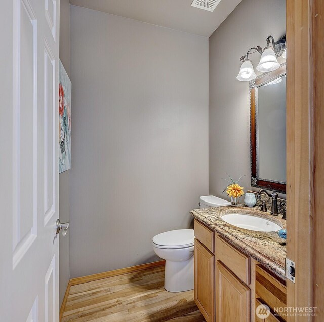 bathroom featuring visible vents, toilet, wood finished floors, baseboards, and vanity