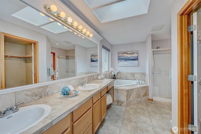 full bath featuring a shower stall, a spacious closet, a garden tub, and a sink