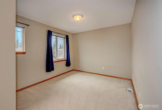 carpeted spare room with visible vents, plenty of natural light, and baseboards