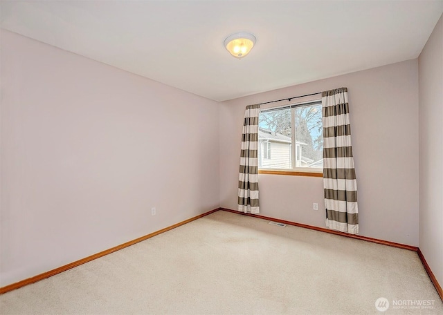 spare room featuring carpet flooring, visible vents, and baseboards