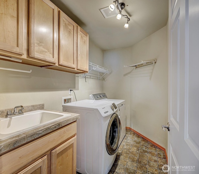 washroom with visible vents, baseboards, cabinet space, a sink, and independent washer and dryer