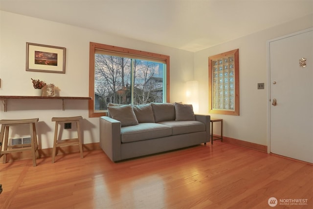 living room with visible vents, baseboards, and light wood-style floors