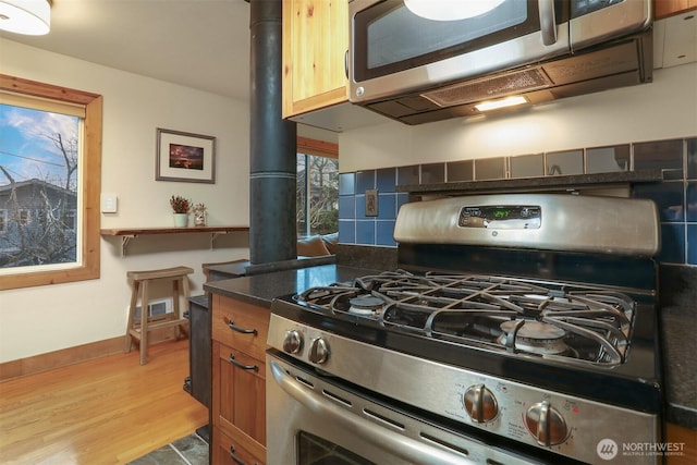 kitchen featuring dark countertops, visible vents, backsplash, wood finished floors, and stainless steel appliances