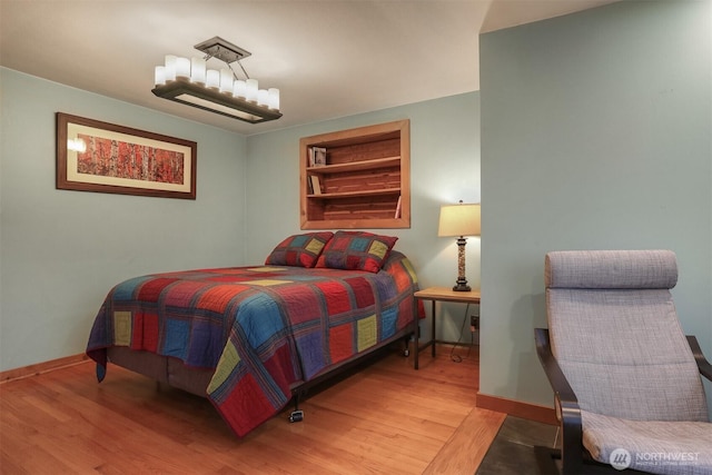 bedroom featuring a notable chandelier, baseboards, and light wood-style floors