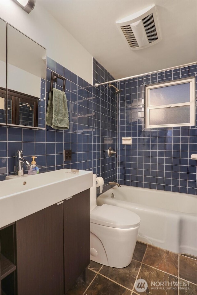 bathroom featuring visible vents, toilet, tile walls, tub / shower combination, and vanity