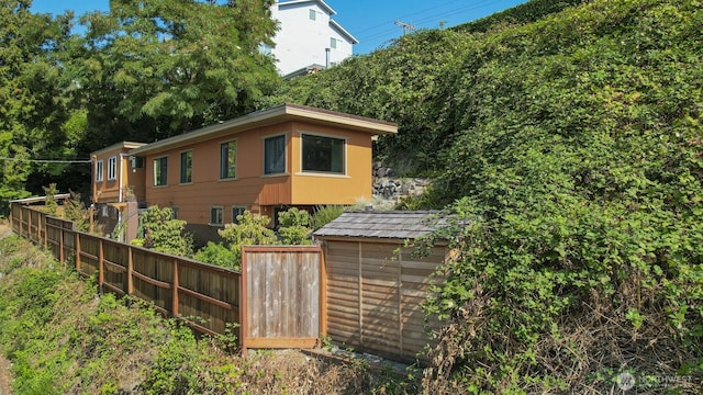 view of side of property featuring a storage shed, an outdoor structure, and fence